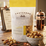Thatcher's Artisan Popcorn bag with caramel corn and nuts on a wooden table.