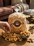 Bag of Thatchers popcorn with scattered popcorn and almonds on a wooden table.