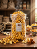Bag of Thacher's Caramel Cheddar popcorn on a wooden table with caramel pieces and popcorn scattered around.