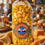 Bag of Fletcher's Cheddar Cheese popcorn on a wooden table with cheddar cheese blocks.