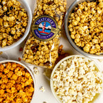 Assorted popcorn in bowls with a bag of Popcorn Time on a white background