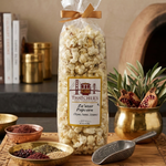 Bag of Thatcher's Za'atar Popcorn on a wooden tray with spices and a plant.