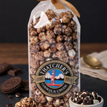 Bag of Thatcher's Caramel Corn with chocolate drizzle and cookies on a dark surface